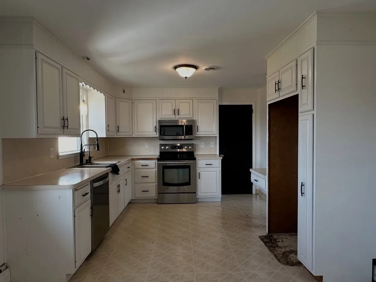 Before: dated white kitchen with laminate counters and vinyl tile floor